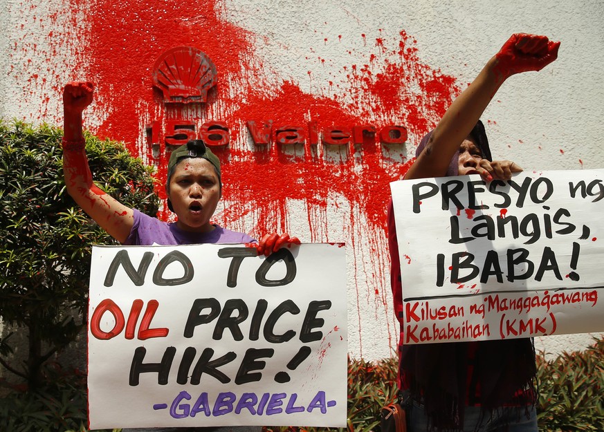 Protesters shout slogans after splashing red paint at the logo of Shell, one of the three big oil companies in the country, to denounce a new round of oil price increase implemented this week, the eig ...