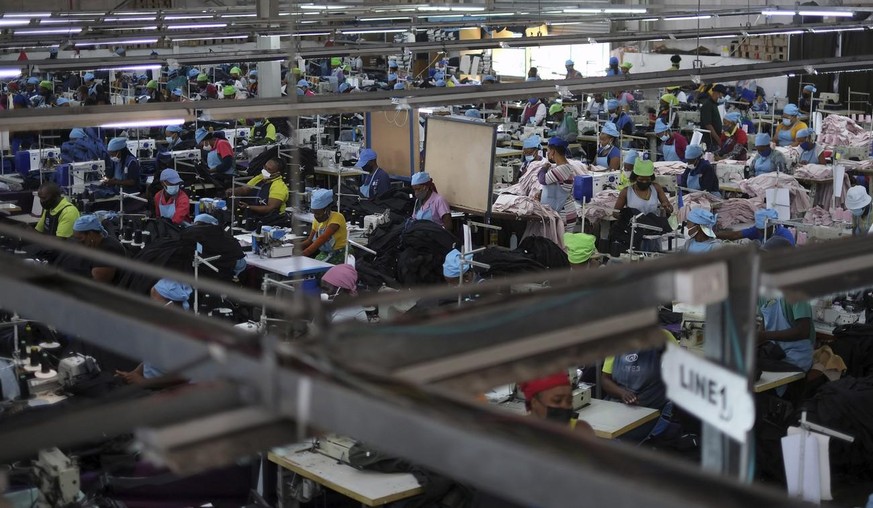 Arbeiterinnen und Arbeiter in einer Bekleidungsfabrik in Maseru, Lesotho, am Donnerstag, 24. Februar 2022. Zu Beginn der Corona-Pandemie brach die globale Modeindustrie angesichts der einbrechenden Na ...