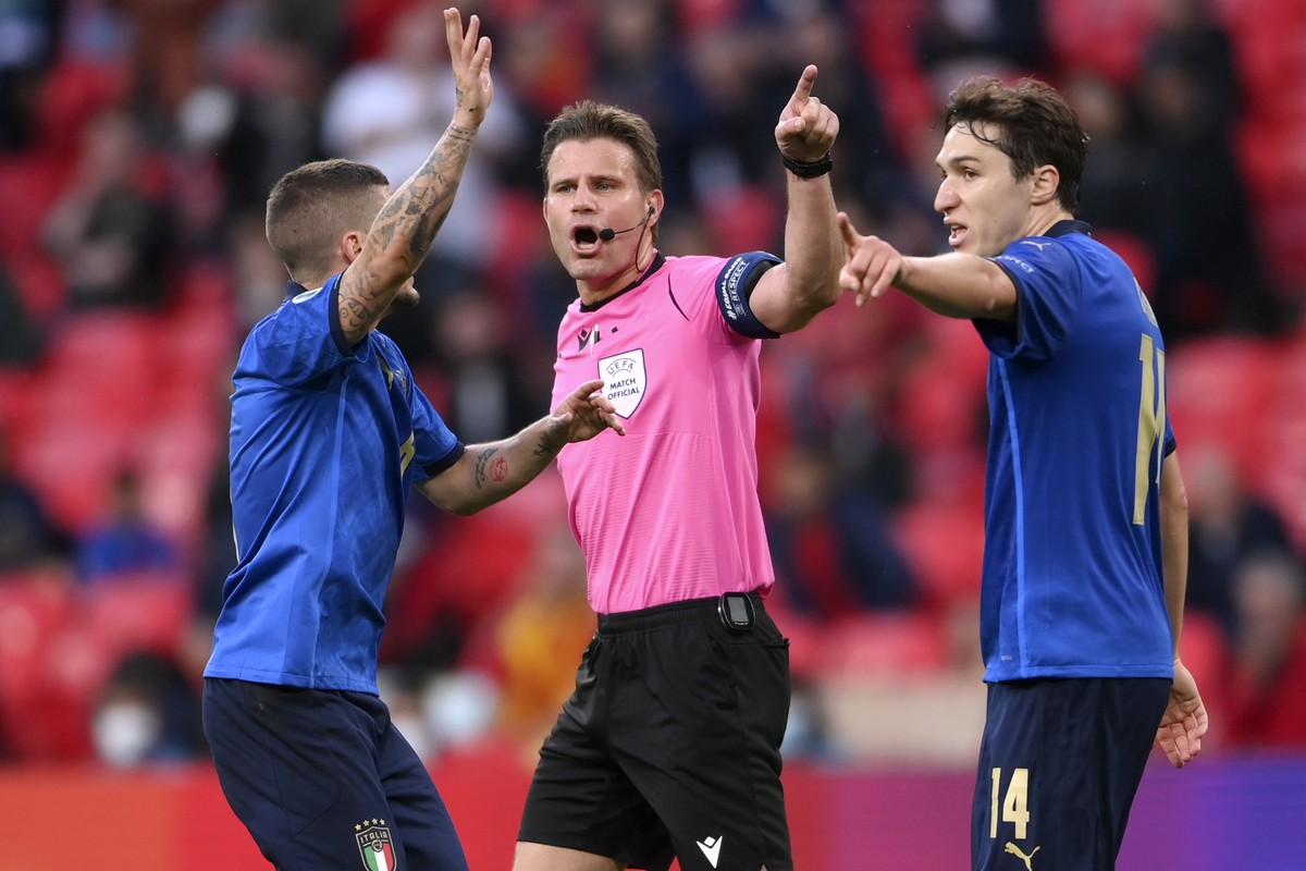 Italy's Marco Verratti, left, and Federico Chiesa protest to German referee Felix Brych during the Euro 2020 soccer semifinal match between Italy and Spain at Wembley stadium in London, Tuesday,  ...