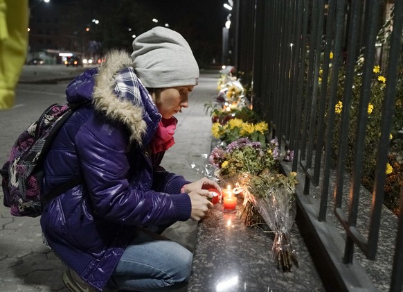 A Ukrainian woman lights a candle to pay tribute to victims of a Russian plane crash, in front of the Russian Embassy in Kiev, Ukraine, Saturday, Oct.31, 2015. A Russian passenger plane has crashed in ...