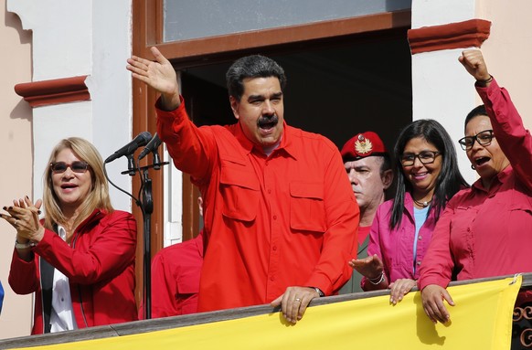 Venezuela&#039;s President Nicolas Maduro, center, and first lady Cilia Flores, left, interact with supporters from a balcony at Miraflores presidential palace during a rally in Caracas, Venezuela, We ...
