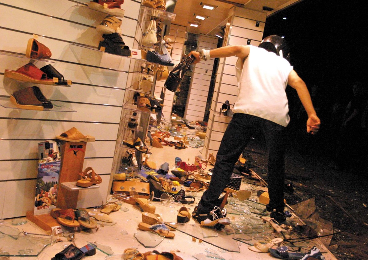 A masked protester is looting a hand bag from the Aeschbach shoes store window shop in downton Geneve, late Sunday night 01 June 2003. Hundreds of anti globalism protesters clashed last night with Swi ...