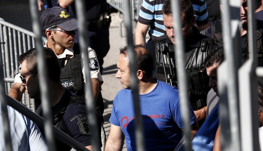 A Turkish military officer, center, is escorted by policemen as he leaves a building of the Greek Asylum Service in Athens, Wednesday, July 27, 2016. Two of the eight Turkish military officers who are ...