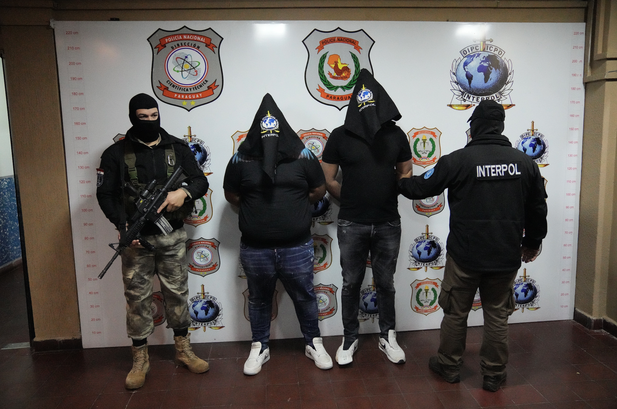 People identified by police as cousins with the same name, Giuseppe Giorgi, both from Italy, center, are shown with their faces covered to the press, by police at the Interpol Office in Asuncion, Para ...