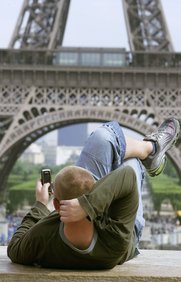 ZUR ABSCHAFFUNG DER ROAMINGGEBUEHREN VON SWISSCOM STELLEN WIR IHNEN AM DONNERSTAG, 19. FEBRUAR 2015, FOLGENDES ARCHIVBILD ZUR VERFUEGUNG – An unidientified man uses a cellular phone next to the Eiffel ...