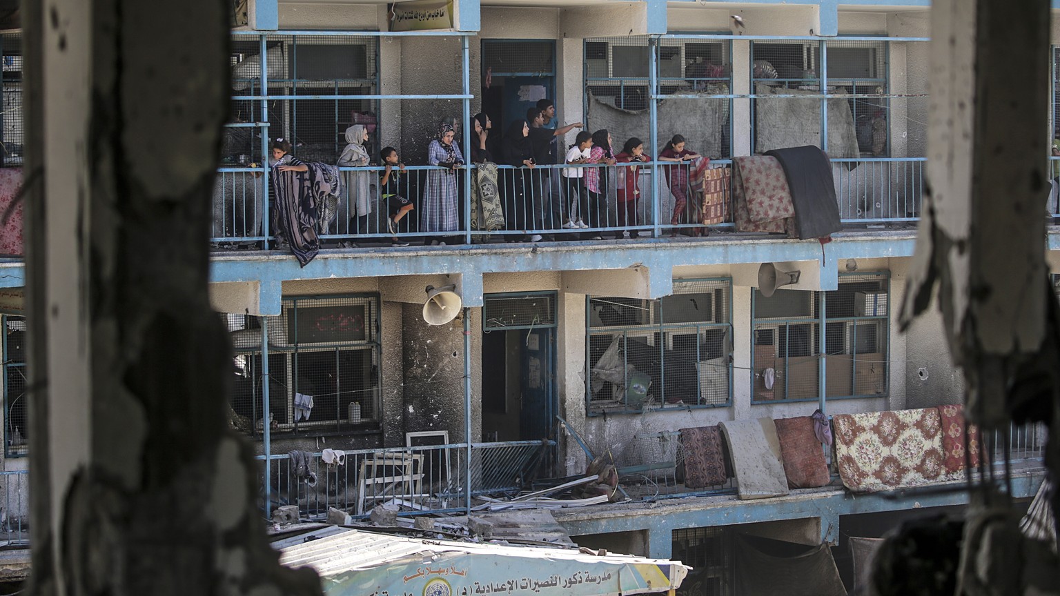 epa11392969 Internally displaced Palestinians look out from the balcony of a damaged UNRWA school building following an Israeli airstrike in Al Nusairat refugee camp in the central Gaza Strip on, 06 J ...