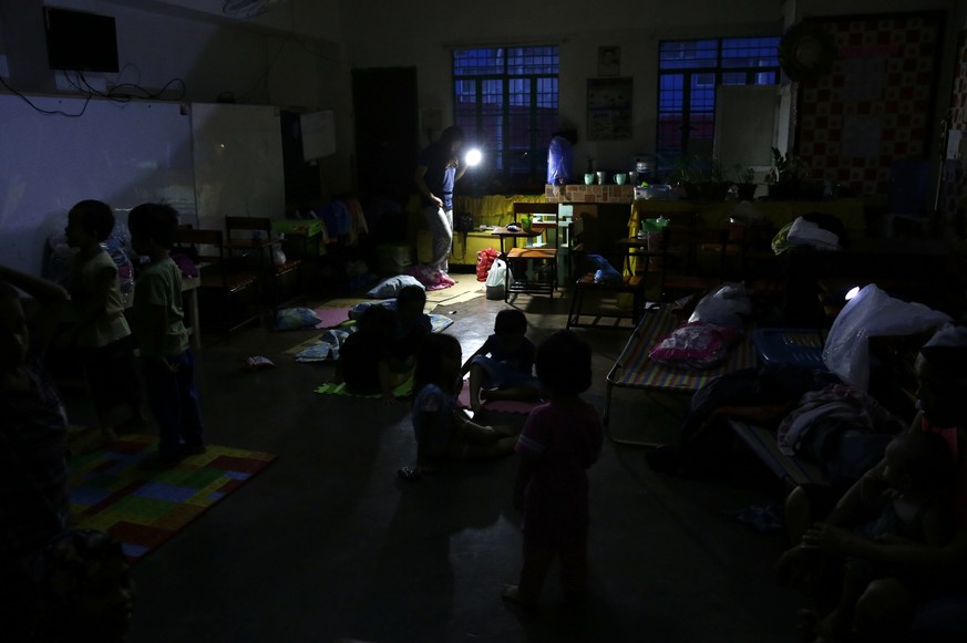 A woman uses a flashlight inside a temporary evacuation center as electricity was shut-off following the onslaught of Typhoon Mangkhut in Tuguegarao city in Cagayan province, northeastern Philippines  ...