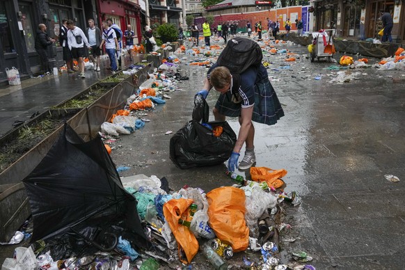 A Scotland fan helps clean up after fans gathered in Leicester Square prior to the Euro 2020 soccer championship group D match between England and Scotland, in London, Friday, June 18, 2021. (AP Photo ...