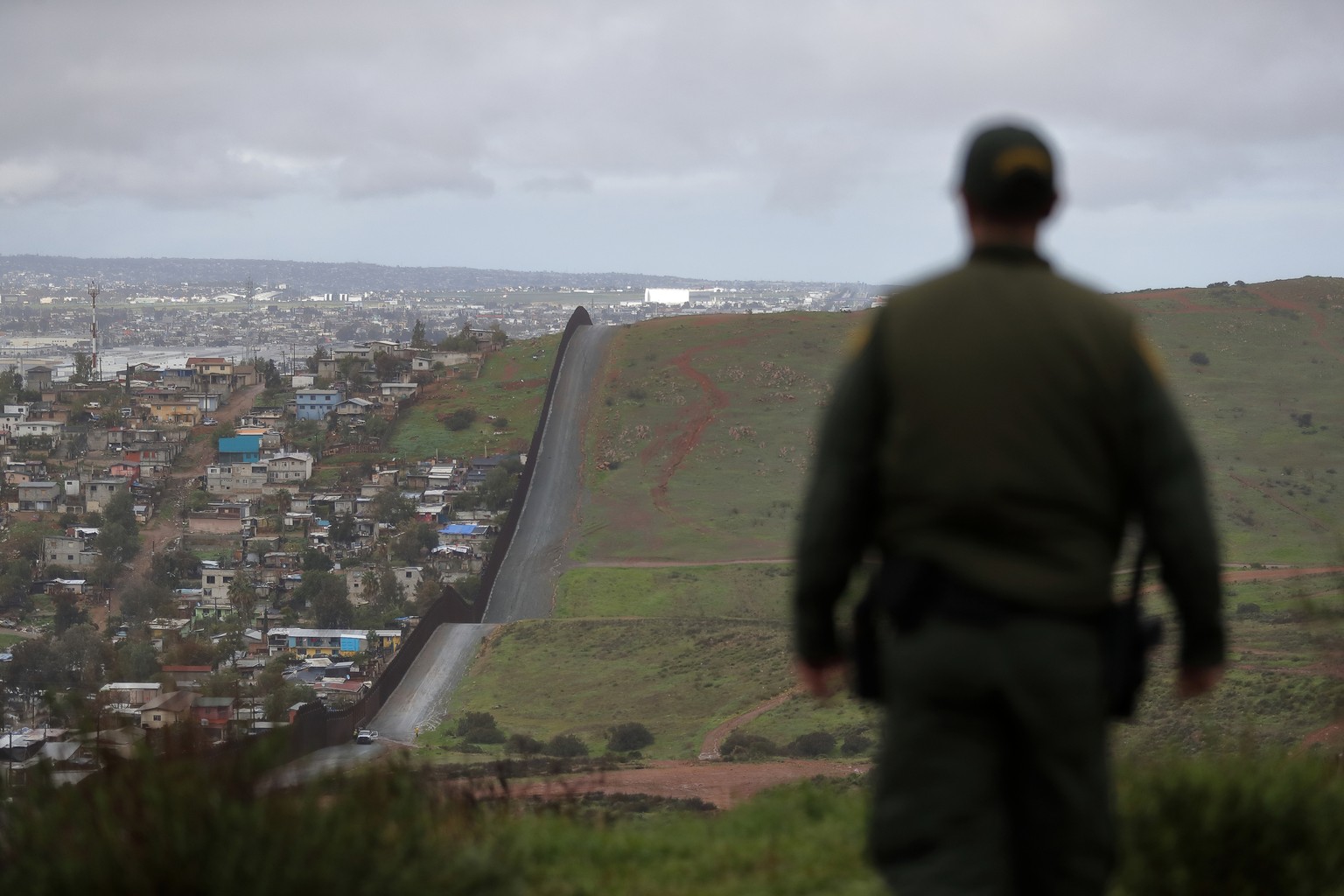 FILE - In this Feb. 5, 2019, file photo, Border Patrol agent Vincent Pirro looks on near a border wall that separates the cities of Tijuana, Mexico, and San Diego, in San Diego. U.S. border authoritie ...