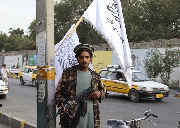 A Taliban fighter holds his weapon under Taliban flags hanging on a street in Kabul, Afghanistan, Monday, Aug. 30, 2021. Many Afghans are anxious about the Taliban rule and are figuring out ways to ge ...
