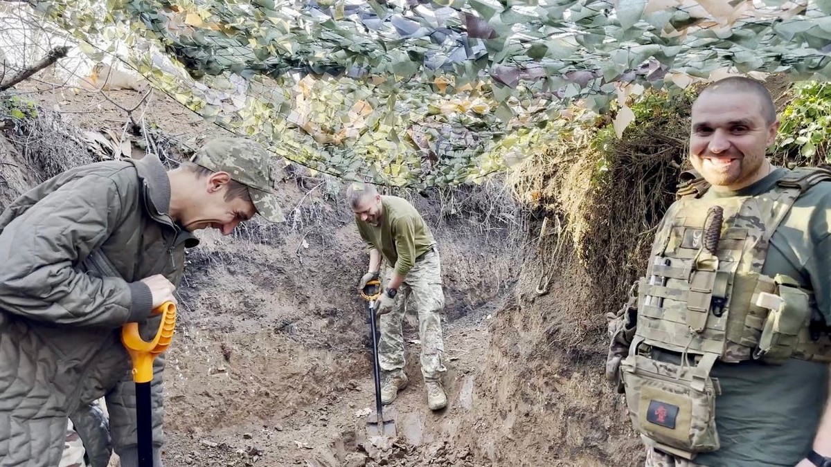 Ukrainische Soldaten machen Spässe, während sie einen Unterstand ausheben.