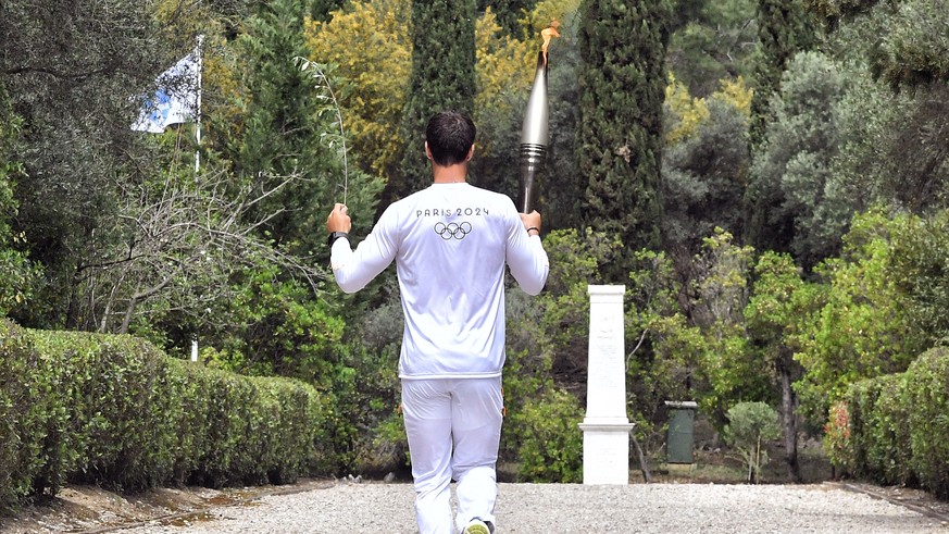 epa11281949 First torchbearer Greek Rowing Olympic Champion Stefanos Ntouskos carries the Olympic Torch during the Lighting Ceremony of the Olympic Flame for the Paris 2024 Olympic Games, in Archaia O ...