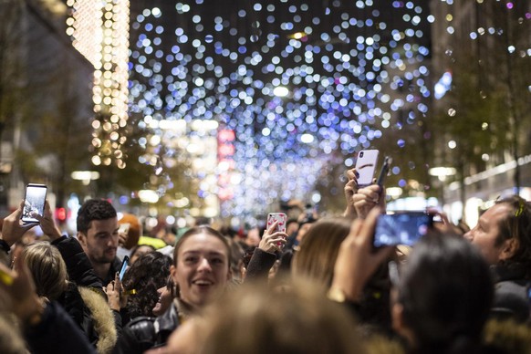 Menschen fotografieren die Weihnachtsbeleuchtung &quot;Lucy&quot; an der Bahnhofstrasse in Zuerich, aufgenommen am Donnerstag, 21. November 2019. (KEYSTONE/Ennio Leanza)