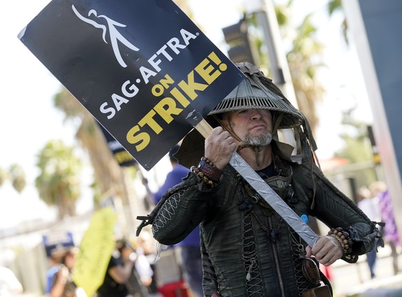 FILE - SAG-AFTRA member Bruce D. Mitchell participates in a post apocalyptic-themed picket line outside Netflix studios, Nov. 8, 2023, in Los Angeles. Hollywood?s actors have voted to ratify the deal  ...