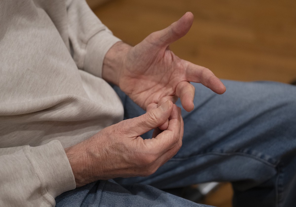 PRODUKTION - 18.02.2026, Hessen, Frankfurt/Main: Ein an Parkinson erkrankter Mann massiert seine Finger bei einer speziellen Tanzstunde, in der Patienten mit neurologischen Krankheiten wie Parkinson l ...