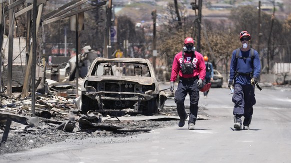 Members of a search and rescue team walk along a street on Saturday, Aug. 12, 2023, in Lahaina, Hawaii. (AP Photo/Rick Bowmer)