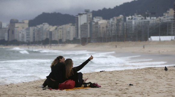 epa05379814 People take a selfie on the beach of Leme in Rio de Janeiro, Brazil, 20 June 2016, as winter arrives to the country. EPA/MARCELO SAYAO