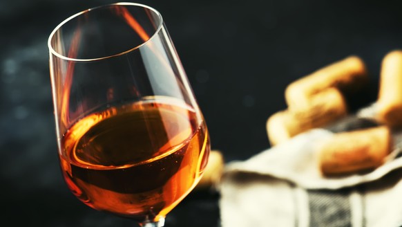 Trendy food and drink, orange wine in glass, gray table, space for text, selective focus