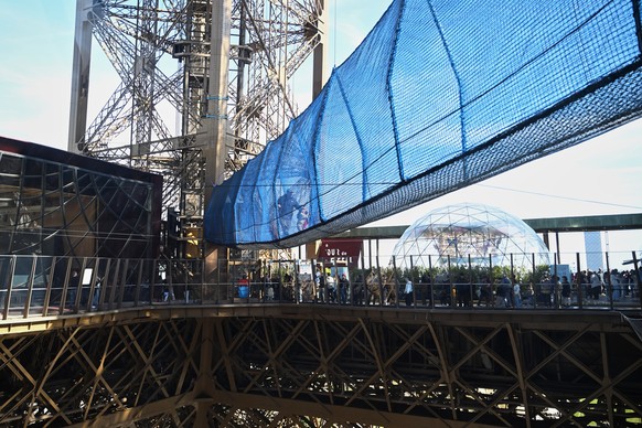Visitors cross the Vertigo of the Tower, an attraction made of a 40-meter-long bridge at a height of 60 meters designed with nets and set up on the 1st floor of the Eiffel Tower, in Paris, Tuesday, Ma ...
