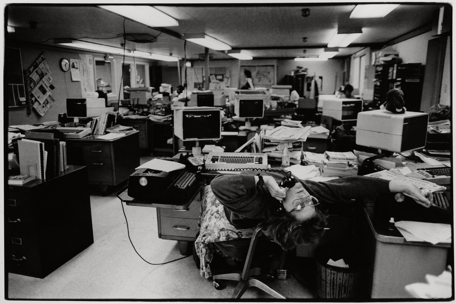 View of an unidentified journalist, leaning back over her chair, as she talks on the telephone in the Hayward Daily Review newsroom, Hayward, California, 1988. (Photo by Bromberger Hoover Photography/ ...