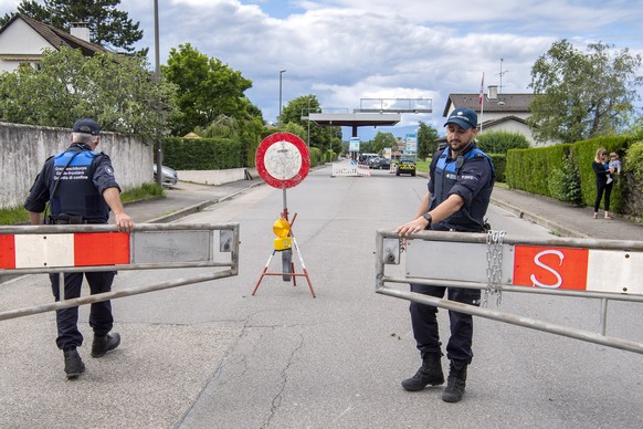 Two border guards opens the barrier that closed access to customs, in Thonex near Geneva, Switzerland, on Sunday, June 14, 2020. Concrete blocks closed the road at the Swiss-French border during the s ...