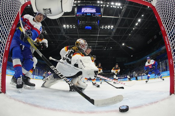 Slovakia&#039;s Kristian Pospisil (88) and Germany goalkeeper Mathias Niederberger (35) both reach for a goal by Slovakia&#039;s Libor Hudacek, right, during a men&#039;s qualification round hockey ga ...