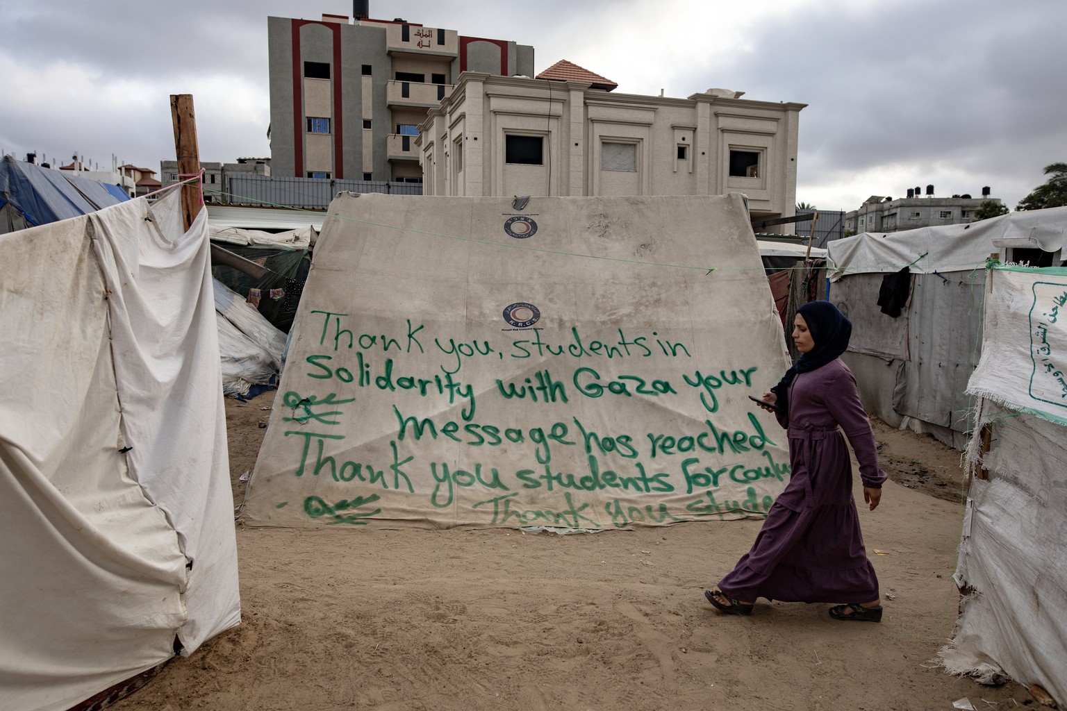 epa11305315 An internally displaced Palestinian woman walks past a tent with a thank you message dedicated to students at the Columbia University in New York, USA, at the Rafah refugee camp in the sou ...