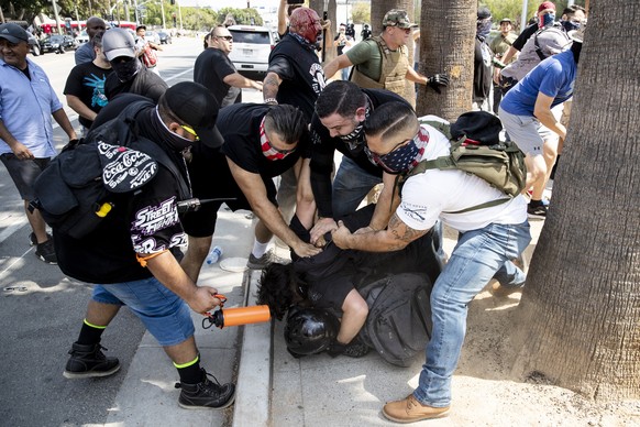 epa09414440 Anti-vaccination demonstrators and a counter protester (on the ground) clash during an anti vaccination protest organized in front of the City Hall in Los Angeles, California, USA, 14 Augu ...