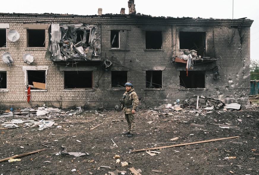 epa11336743 A Ukrainian police officer inspects a damaged building during the evacuation of local people from territories bordering Russia, in the city of Vovchansk, Kharkiv region, northeastern Ukrai ...