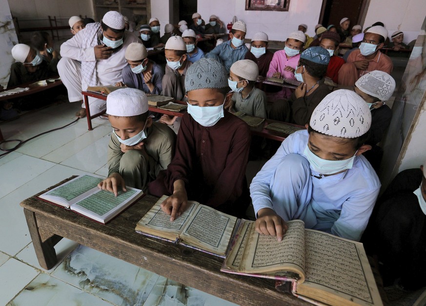 Children wearing face masks to prevent the spread of coronavirus read the Quran at a . religious school in a mosque, in Karachi, Pakistan, Saturday, Sept. 19, 2020. (AP Photo/Fareed Khan)