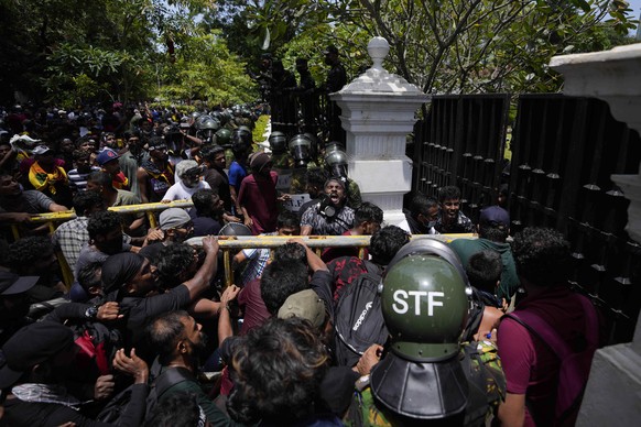 Protesters use an iron barricade to break the gate as they storm the compound of Sri Lankan Prime Minister Ranil Wickremesinghe&#039;s office, demanding he resign after president Gotabaya Rajapaksa fl ...