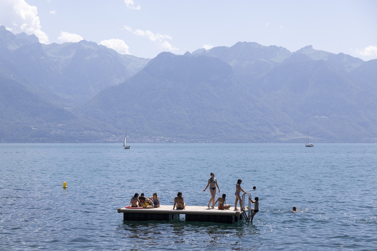 People are on a platform on the lake and enjoy the warm summer weather on the shores of Lake Geneva in front of the Swiss Alps mountains, in Vevey, Switzerland, Saturday, July 8, 2023 (KEYSTONE/Cyril  ...
