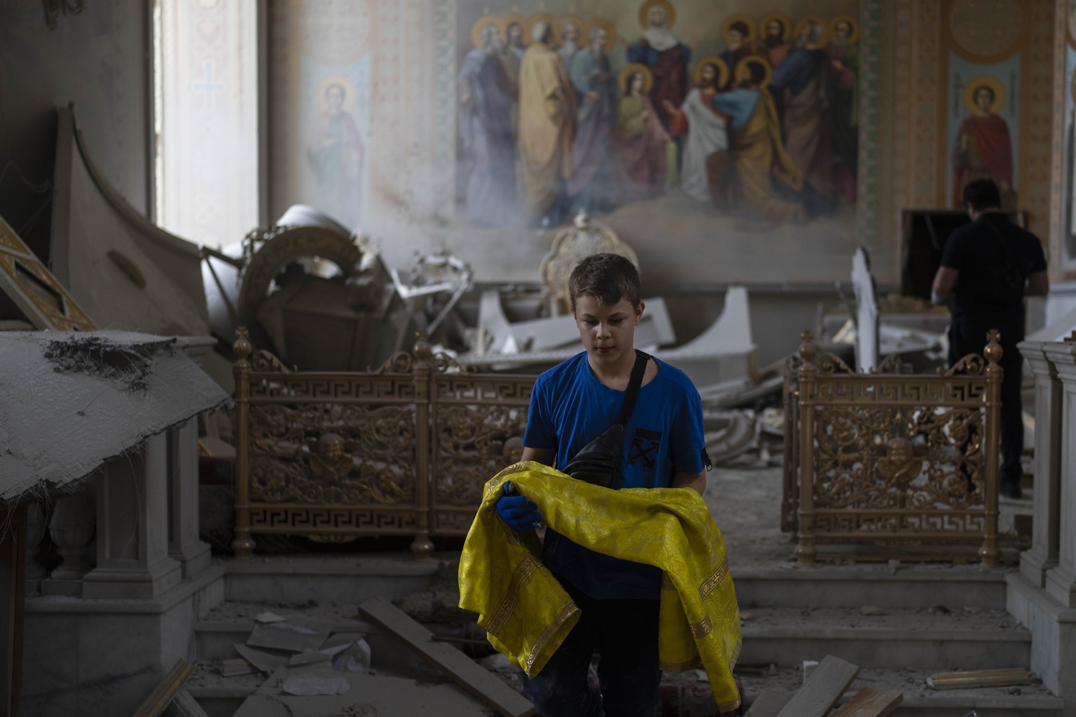 A boy helps salvage items at the Odesa Transfiguration Cathedral after it was heavily damaged in Russian missile attacks in Odesa, Ukraine, Sunday, July 23, 2023. (AP Photo/Jae C. Hong)