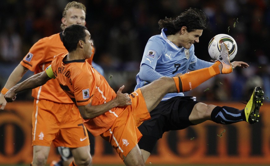 Uruguay's Edison Cavani, right, competes for the ball with Netherlands' Giovanni van Bronckhorst, front left, during the World Cup semifinal soccer match between Uruguay and the Netherlands at the Gre ...