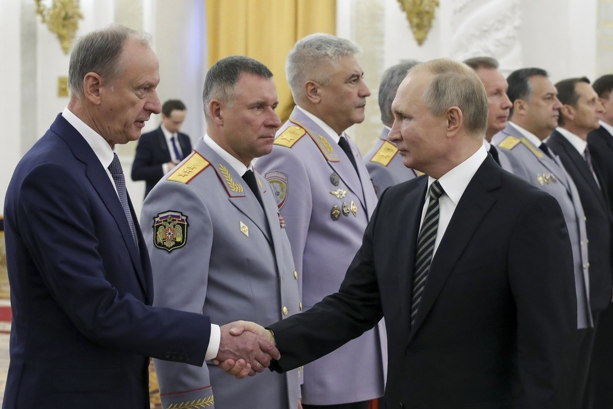 Russian President Vladimir Putin shakes hands with Russian Security Council chairman Nikolai Patrushev, left, as he greets senior military officers during a meeting in Moscow, Russia, Wednesday, Nov.  ...