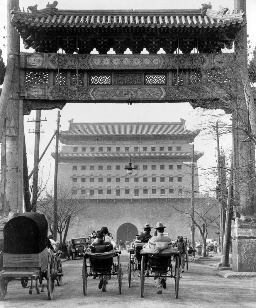 Rikschas fahren durch ein Pailou (Scheintor), im Hintergrund das südliche Stadttor Zhengyangmen beim Platz des Himmlischen Friedens (um 1925).