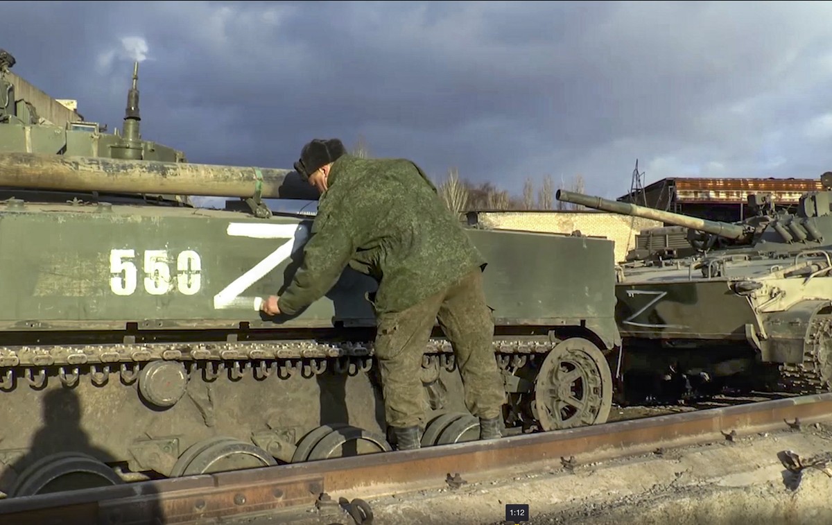 epa09829115 A handout still image taken from handout video made available by the Russian Defence ministry press-service shows a Russian soldier marks an armoured personnel carrier that was abandoned b ...