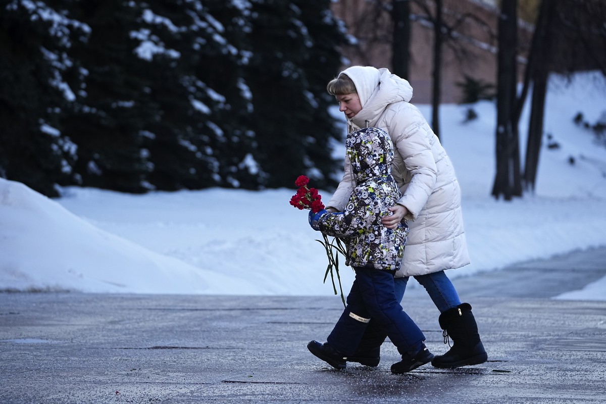 One of wives of Russian soldiers mobilized for fighting in Ukraine walks with her child to lay flowers at the Unknown Soldier's Tomb at the Kremlin wall in Moscow, Russia, Saturday, Jan. 13, 2024 ...