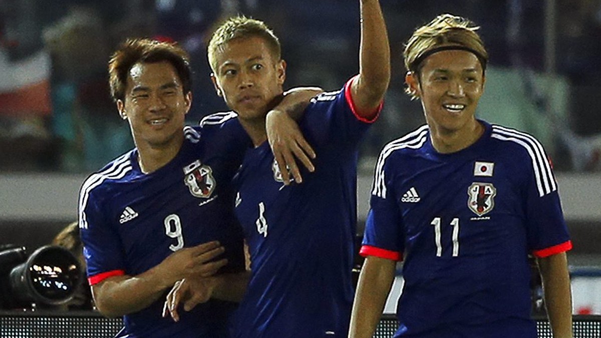 epa04793611 Japan's forward Keisuke Honda (C) celebrates with his teammates Shinji Okazaki (L) and Takashi Usami (R) after scoring the opening goal during the international friendly soccer match ...