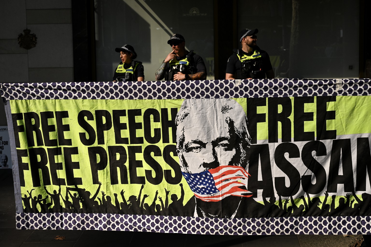 epa11167259 Victorian Police officers stand behind a banner at a 24-hour vigil for Julian Assange in Melbourne, Australia, 20 February 2024. WikiLeaks founder Julian Assange&#039;s two-day extradition ...