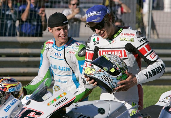 Newly crowned 125cc World Champion, Swiss motorcycle pilot Thomas Luethi, left, and MotoGP World Champion Valentino Rossi from Italy place their helmets onto their bikes for a end of season photo sess ...