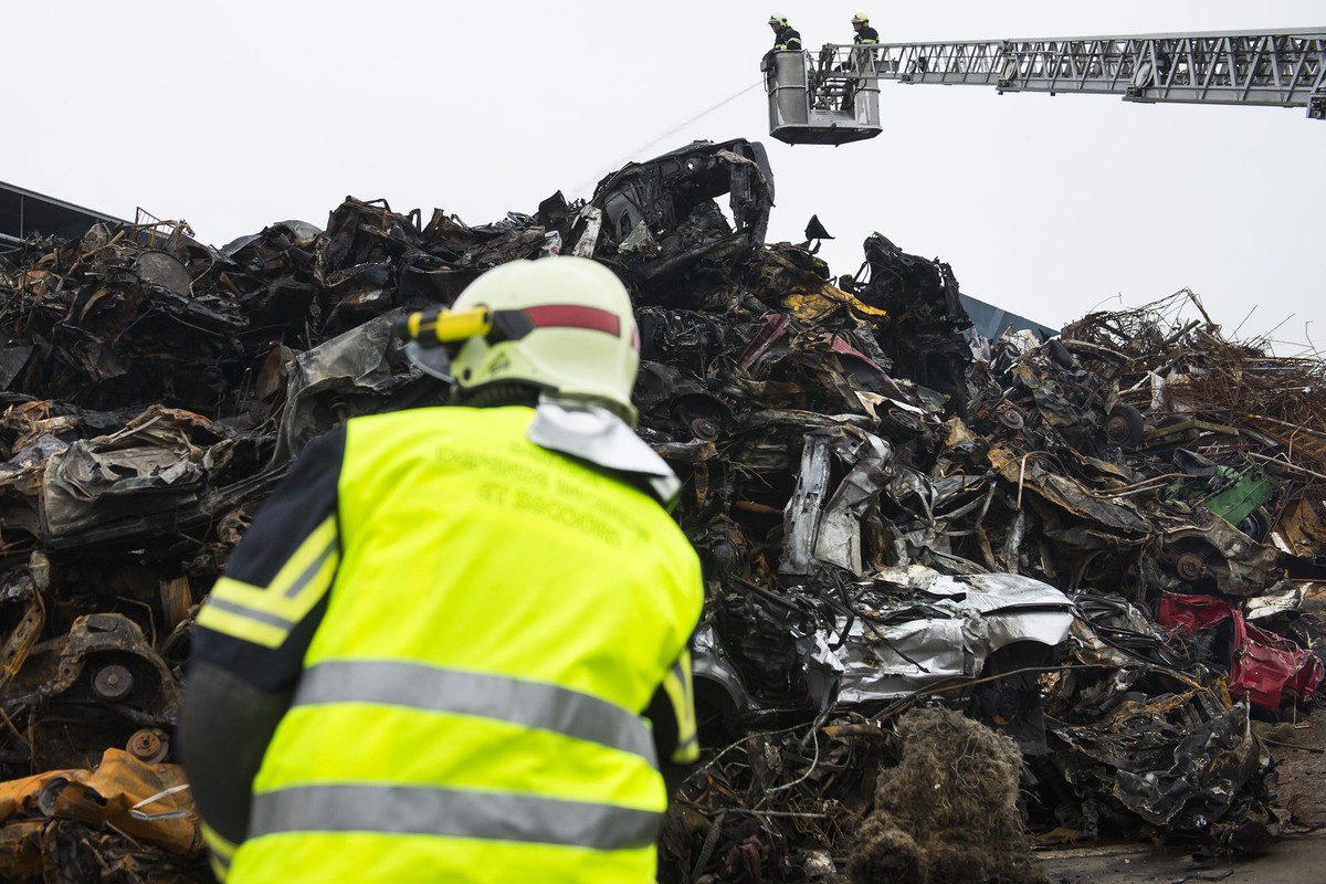 Pompiers et ouvriers de l'entreprise refroidissent et enlevent les carcasses de voitures brulees un jour apres l'incendie de carcasses de voitures chez Thevenaz Leduc ce jeudi 4 decembre 201 ...