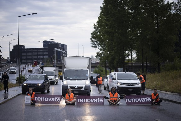 Environmental activists of Renovate Switzerland sit down on the road during a roadblock action on the motorway A1 exit in Zuerich, Switzerland on June 19, 2023. (KEYSTONE/Michael Buholzer)