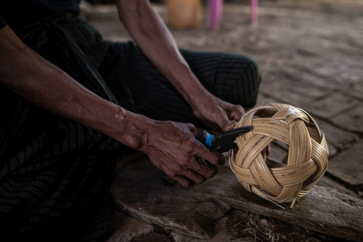 This photo taken on May 8, 2025 show a man weaving cane into a chinlone ball, used in the ancient Myanmar game considered a blend between sport and art, at a workshop in Hinthada township in the Irraw ...