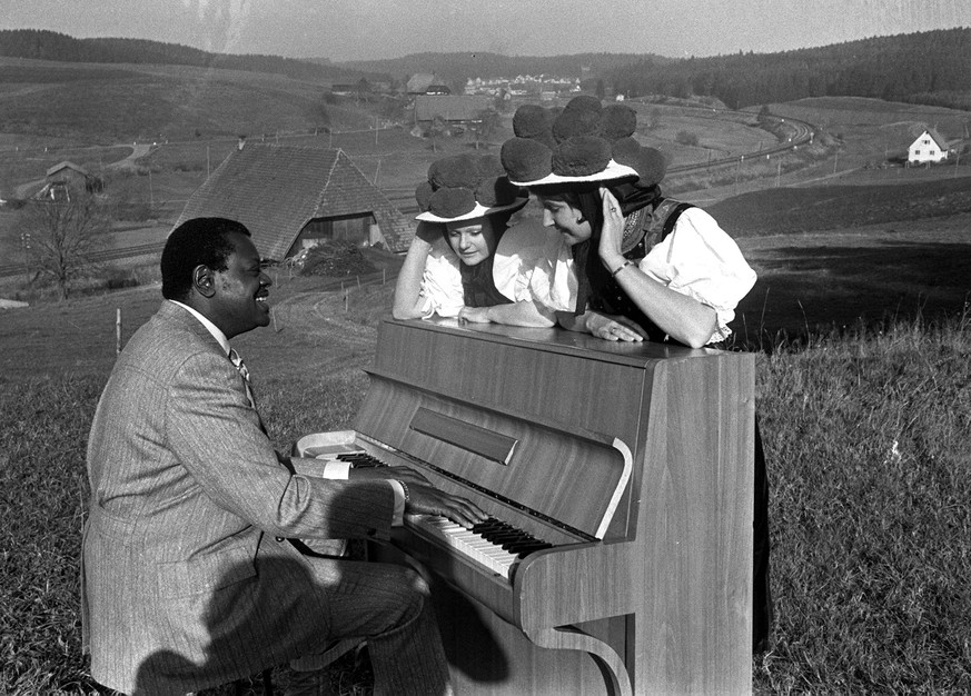 Villingen, West Germany, 14th November 1970, American jazz pianist Oscar Peterson entertains two traditionally dressed ladies on the piano in the middle of a field