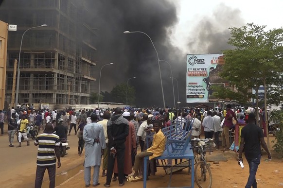 With the headquarters of the ruling party burning in the back, supporters of mutinous soldiers demonstrate in Niamey, Niger, Thursday, July 27 2023. Governing bodies in Africa condemned what they char ...