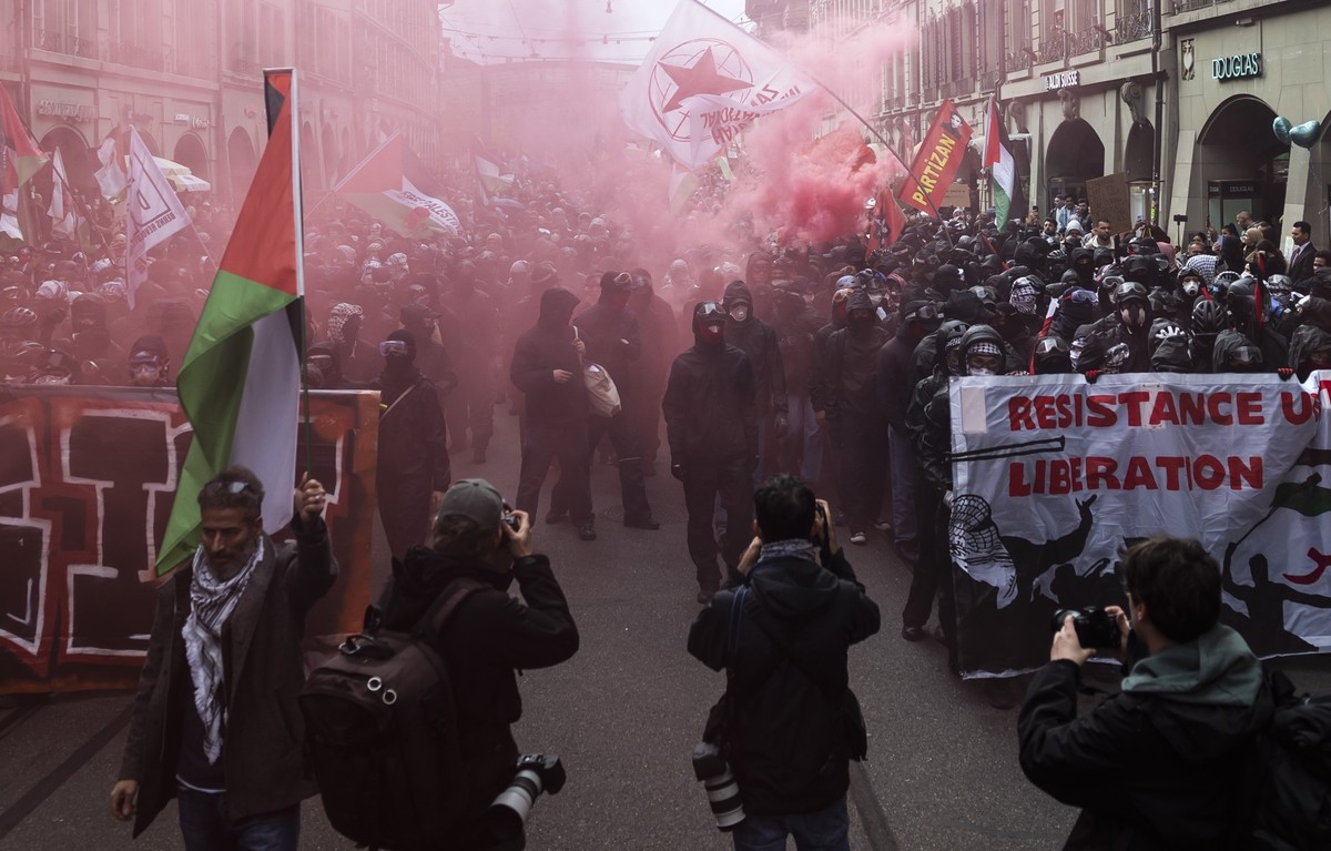 People hold banners and wave Palestinian flags during an unauthorized rally in solidarity with the Palestinian people in Bern, Switzerland, 11 October 2025. (KEYSTONE/Peter Klaunzer)
