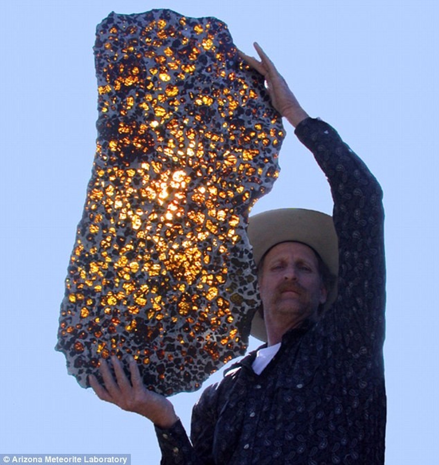 Fukang meteorite: Marvin Killgore of the Arizona Meteorite Laboratory shows the sun shining through a polished piece of Fukang rock.  https://meteoritelab.com/2020/08/cowboy-and-meteorite/
