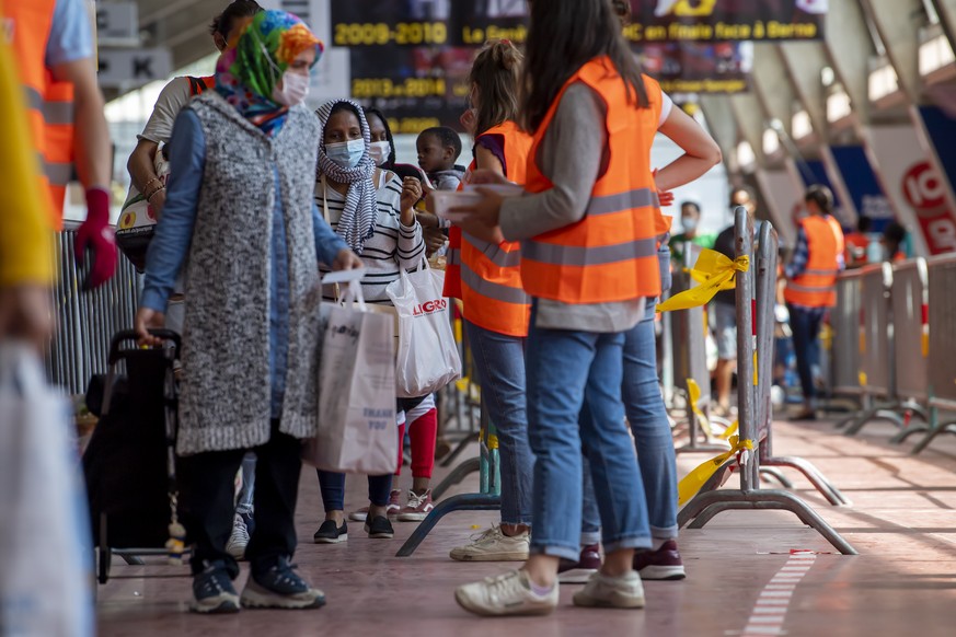 People queue to receive bags with free food and essential products received from donations at the ice stadium Les Vernets, in Geneva, Switzerland, Saturday, May 30, 2020. Following the pandemic corona ...