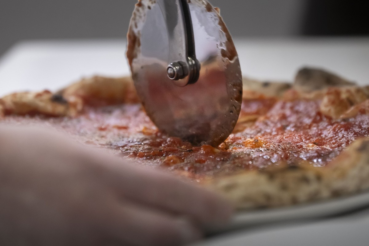 Eine Pizza wird mit einem Pizzarad zerteilt am Montag, 22. April 2024 an der 4. Schweizermeisterschaft im Pizzabacken in Giubiasco. Etwa 100 Teilnehmer versuchen mit ihren Pizzas den Titel des Schweiz ...